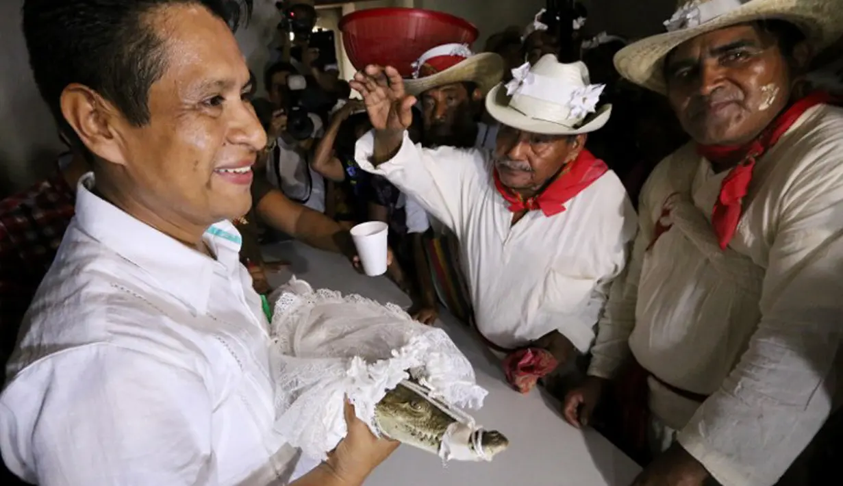 Wali Kota San Pedro Huamelula, Joel Vasque (kiri) menikahi seekor buaya di Oaxaca, Meksiko, 30 Juni 2015. Pernikahan ini bertujuan untuk mendatangkan hasil laut yang melimpah kepada penduduk nelayan di desa setempat. (AFP PHOTO/MARIO JIMENEZ)
