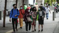 Para pekerja yang mengenakan masker berjalan kaki setelah meninggalkan perkantorannya di Jakarta, Rabu (2/2/2022). Satgas Penanganan COVID-19 turut mencatat sebanyak 25 orang meninggal dunia, membuat total angka kematian mencapai 144.373 orang. (Liputan6.com/Faizal Fanani)