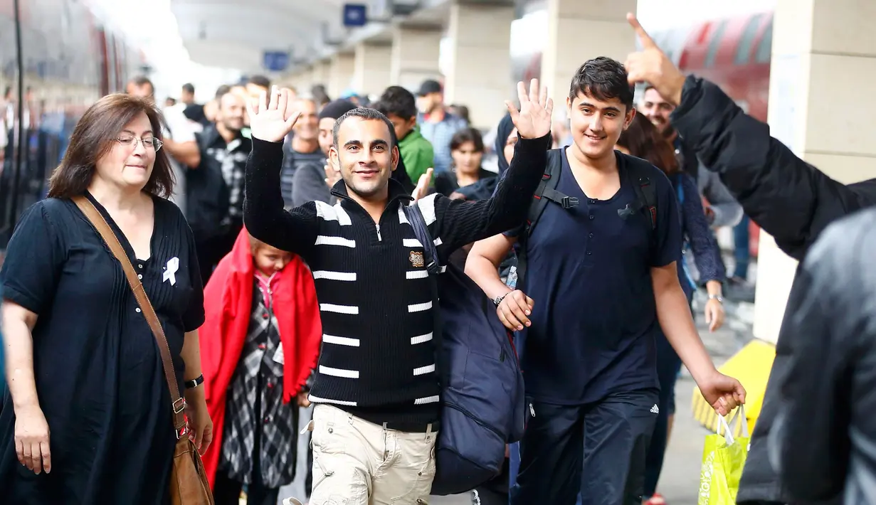Seorang imigran tersenyum dan melambaikan tangan saat tiba di stasiun Wina, Austria, Sabtu (5/9/2015). Sekitar 2.000 imigran menembus Austria setelah pemerintah Hungaria mengizinkan para pencari suaka ke negara selanjutnya. (REUTERS/Dominic Ebenbichler)