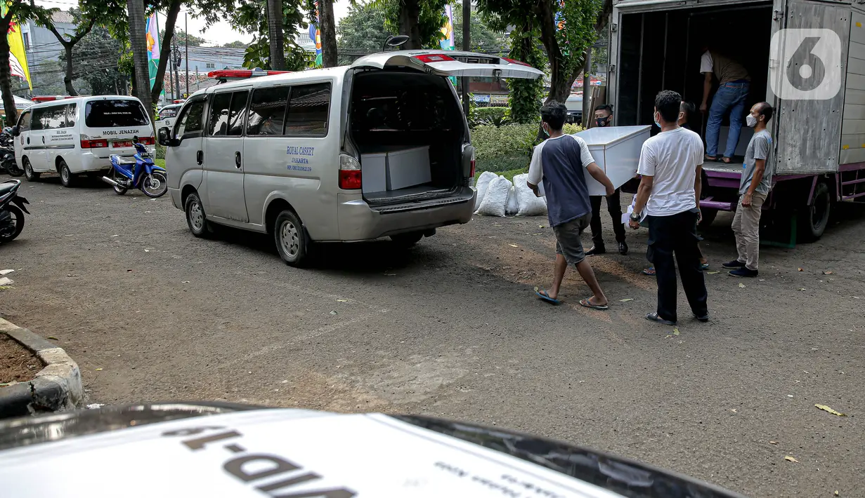 Petugas menurunkan peti jenazah COVID-19 untuk didistribusikan ke rumah sakit di TPU Petamburan, Jakarta, Selasa (6/7/2021). Pemprov DKI Jakarta melalui Dinas Pertamanan dan Hutan menyediakan peti jenazah gratis untuk rumah sakit dan pasien COVID-19 di seluruh DKI. (Liputan6.com/Faizal Fanani)