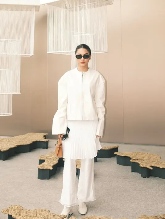 Azizah Salsha tampil dalam balutan serba putih di Jakarta Fashion Week 2025 dengan gaya yang jauh dari kata membosankan. Mengusung konsep layering yang unik, ia memadukan jaket oversized berpotongan clean dengan rok lipit yang jatuh tepat di atas celana putih, menciptakan siluet modern yang menarik. Sentuhan aksesori seperti kacamata hitam dan tas kecil berwarna cokelat memberi aksen yang kontras dan memperkaya penampilannya. [@azizahsalsha_].