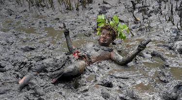 Seorang pria mengambil bagian dalam tradisi mandi lumpur yang dikenal sebagai Mebuug-buugan di Desa Kedonganan, Bali, 4 Maret 2022. Mebuug-buugan diadakan sehari setelah Nyepi yang bertujuan untuk menetralkan sifat buruk. (SONY TUMBELAKA/AFP)