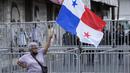 Seorang wanita memegang bendera Panama saat anggota serikat guru yang mogok memprotes selama pawai menuju Majelis Nasional di Panama City, Senin (11/7/2022). Masker tidak lagi diperlukan kecuali di rumah sakit dan transportasi umum. (AP Photo/Arnulfo Franco)
