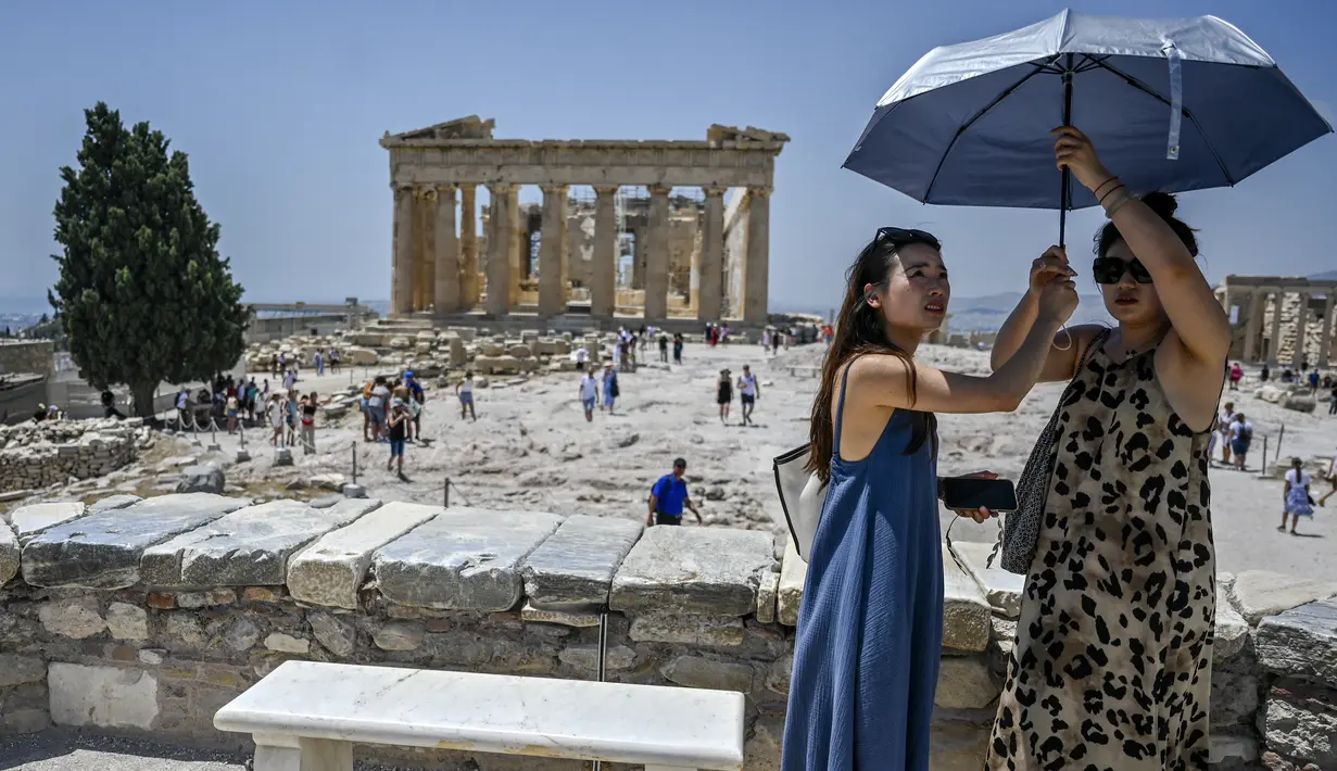 Wisatawan melindungi diri dari matahari saat mengunjungi Acropolis di Athena, Yunani, Minggu (24/7/2022). Negara ini berada dalam cengkeraman gelombang panas yang dimulai pada 23 Juli dan akan berlangsung beberapa hari. Suhu diperkirakan akan mencapai 42 derajat Celcius (107 derajat Fahrenheit) di beberapa daerah.
(Louisa GOULIAMAKI / AFP)