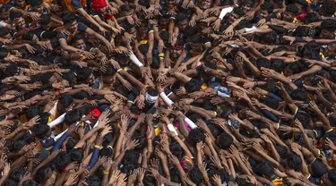 Orang-orang memberikan penghormatan sebelum membentuk piramida manusia untuk mencapai pot tanah yang menjorok  saat merayakan festival Hindu Janmashtami, festival yang menandai kelahiran Dewa Hindu Krishna, di Mumbai, India, Selasa, 27 Agustus 2024. (AP Photo/Rafiq Maqbool)