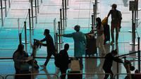 Pekerja mengenakan pakaian pelindung mengarahkan penumpang yang tiba dari Manila untuk karantina di bandara internasional Hong Kong, Jumat (1/4/2022). Penerbangan mulai mendarat di Hong Kong Jumat (1/4) setelah pihak berwenang mencabut larangan tindakan COVID-19. (AP Photo/Kin Cheung)
