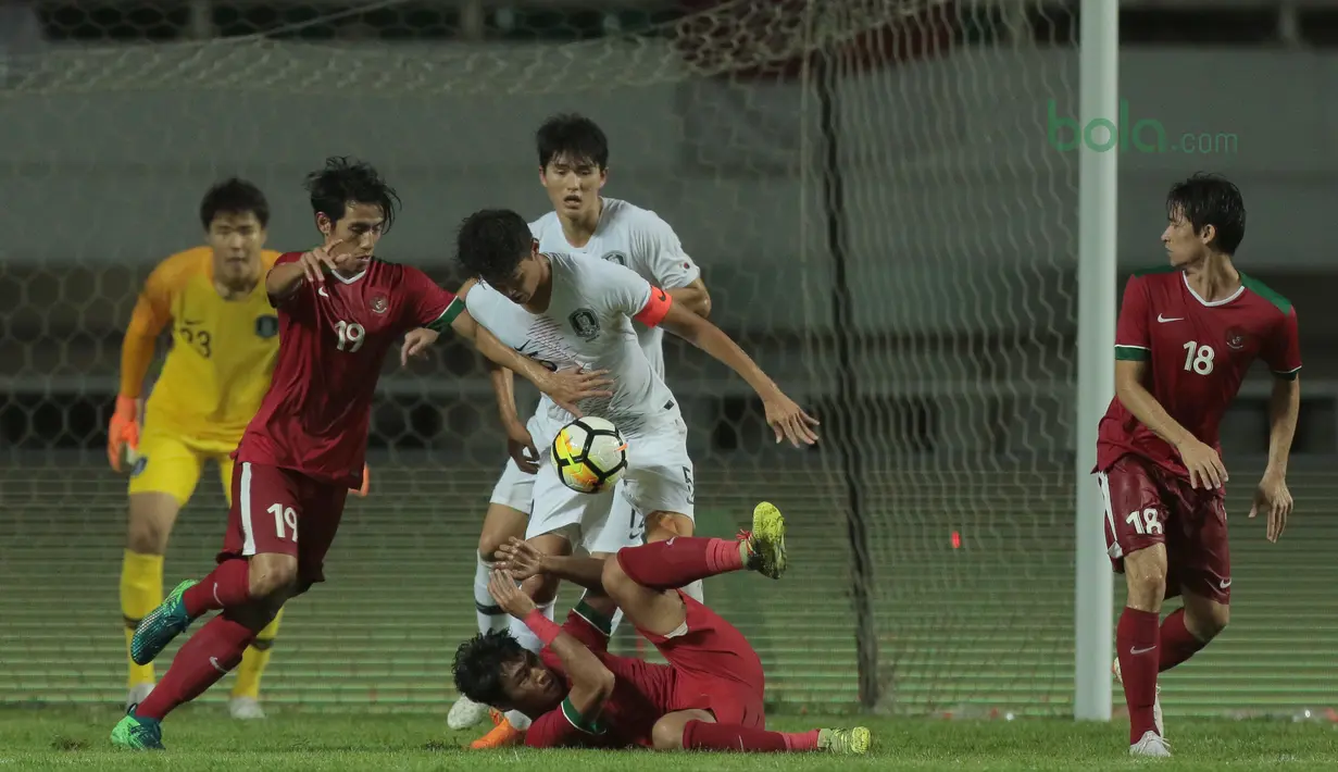 Pemain Timnas Indonesia dan Pemain Korea Selatan U-23 berebut bola pada laga uji coba di Stadion Pakansari, Bogor, (23/6/2018).  Indonesia U-23 kalah 1-2 dari Korea U-23. (Bola.com/Nick Hanoatubun)