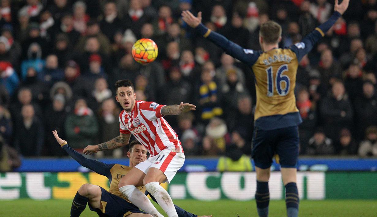 Pemain Arsenal, Laurent Koscielny (kiri)  menghalau bola dari kejaran pemain Stoke City, Mato Joselu (tengah) pada lanjutan Liga Premier Inggris di Stadion Britannia, Stoke-on-Trent, Minggu (17/1/2016).  (AFP Photo/Oli Scarff)