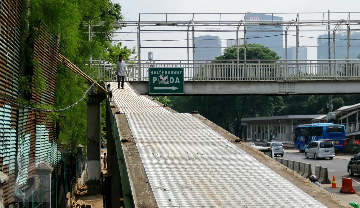Warga melewati JPO sisi barat Polda Metro Jaya di Jalan Jenderal Sudirman, Jakarta, meski sudah ditutup dan dibongkar, Senin (23/11). Pembongkaran dilakukan karena pekerjaan konstruksi bawah tanah untuk perbaikan saluran air. (Liputan6.com/Yoppy Renato)