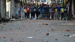 Sejumlah warga Kashmir saat bentrok dengan petugas polisi di Srinagar, India (11/7). Bentrokan bermula karena adanya kasus pembunuhan terhadap seorang pemberontak muda yang populer di India. (AFP PHOTO/Tauseef MUSTAFA)