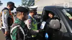 Petugas gabungan dari Kepolisian, TNI dan Dinas Perhubungan (Dishub) DKI Jakarta melakukan himbauan kepada pengendara mobil di perempatan lampu merah Kanal Banjir Timur (KBT), Jakarta, Selasa (5/3/2024). (merdeka.com/Imam Buhori)