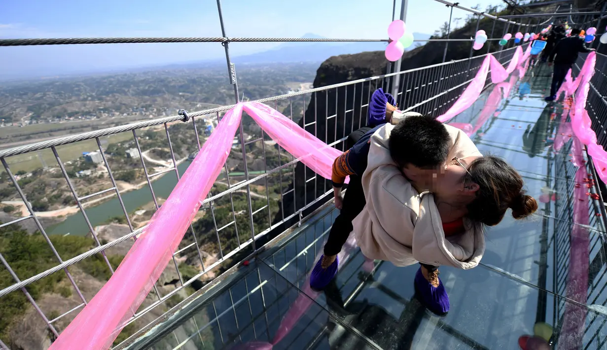 Sepasang pria dan wanita berciuman diatas sebuah jembatan kaca saat mengikuti kontes berciuman di Hari Valentine di Pingjiang, Provinsi Hunan, China (14/2). Setiap kontestan membawa pasangannya dan beradu dengan peserta lainnya. (STR / AFP)