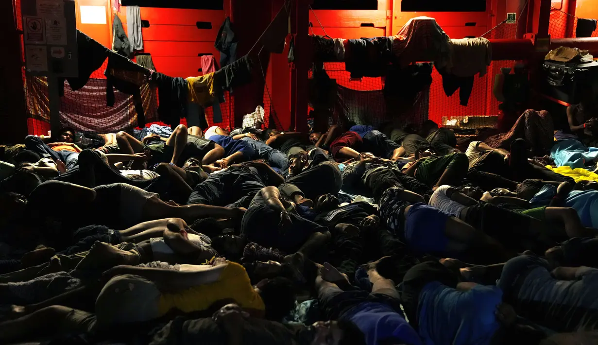 Para migran tidur di geladak kapal penjaga pantai Open Arms LSM Spanyol setelah mereka diselamatkan dari perairan terbuka selama operasi di zona perairan internasional, di laut Mediterania, Selasa dini hari, 20 September 2022. Sekitar empat ratus migran dari Mesir, Suriah, Pakistan, Bangladesh, Eritrea, Sudan, Ethiopia, dan Somalia, diselamatkan oleh anggota awak LSM Open Arms. (AP/Petros Karadjias)