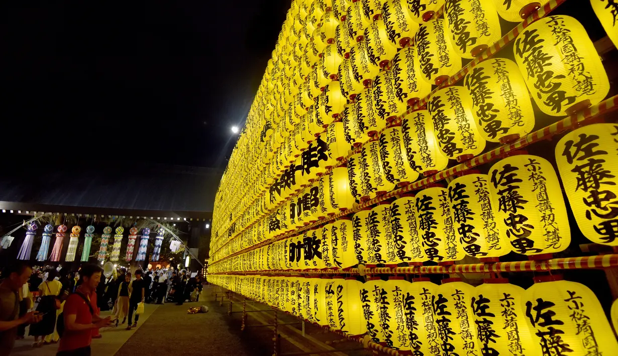 Sejumlah pengunjung melihat lentera yang memeriahkan Festival Mitama di Kuil Yasukuni, Tokyo, Jepang, (13/7). Sekitar 30.000 lentera menerangi daerah terseubt untuk mengenang korban perang.  (AFP Photo/Toru Yamanka)