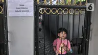 Seorang anak berada di balik pagar saat menjalani isolasi mandiri di permukiman warga RT 003 RW 003, Kelurahan Cilangkap, Kecamatan Cipayung, Jakarta, Selasa (25/5/2021). Jumlah warga yang tepapar Covid-19 di wilayah ini bertambah menjadi 104 orang. (merdeka.com/Iqbal S Nugroho)