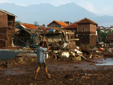 Warga mengangkat sepeda miliknya pasca banjir bandang yang menerjang Kampung Cimacan, Kecamatan Tarogong Kidul, Kabupaten Garut, Kamis (22/9). Berdasarkan data sementara Basarnas Jabar korban tewas 23 orang dan belasan hilang. (Liputan6.com/Johan Tallo)
