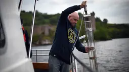 Ahli genetika Universitas Otago Profesor Neil Gemmell mengambil sampel air dari perairan Loch Ness, Drumnadrochit, Skotlandia, 11 Juni 2018. Tim dari Selandia Baru menguji kebenaran dari keberadaan moster raksasa Loch Ness. (Andy Buchanan/AFP)