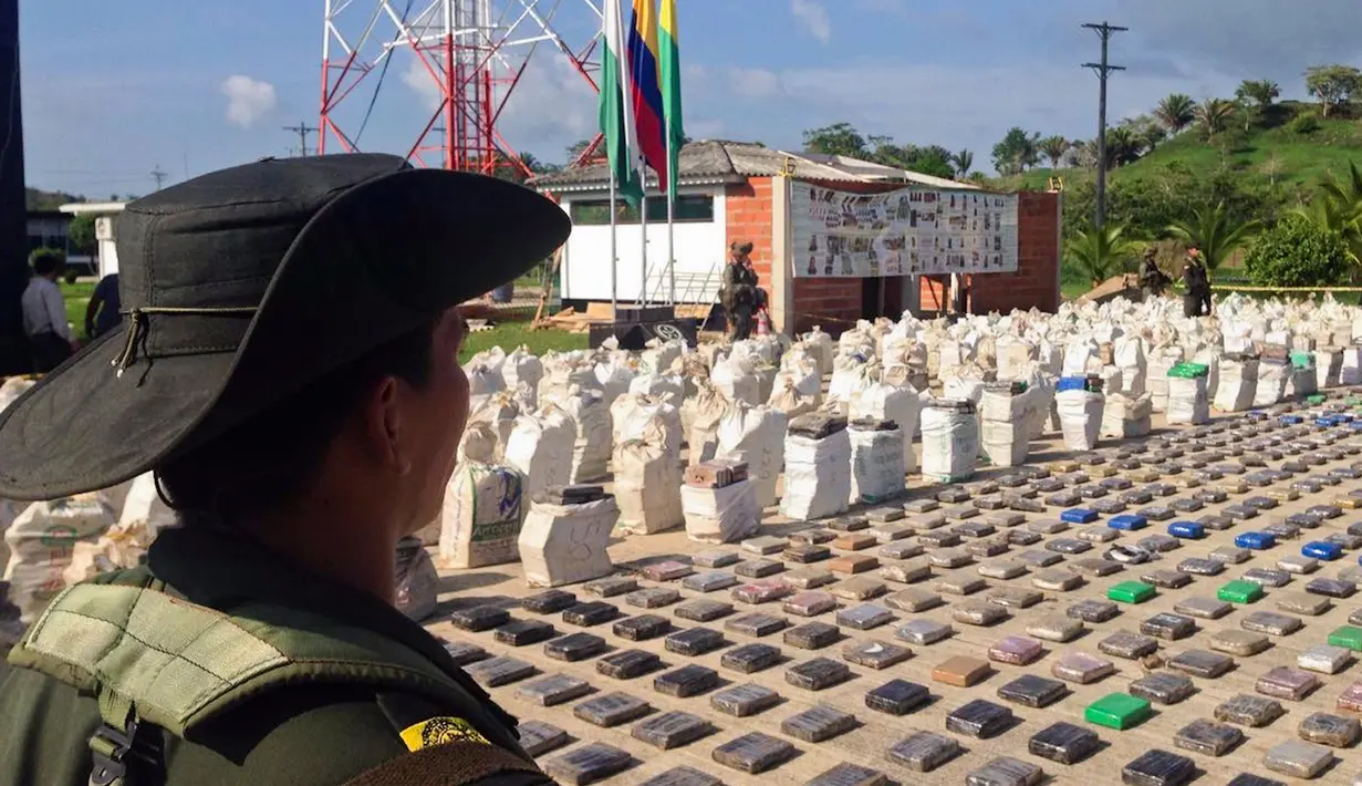 Foto yang dirilis kepolisian Kolombia terlihat petugas berdiri di dekat  8 ton paket kokain yang disita di sepanjang wilayah perbatasan dengan Panama, Minggu (15/5). Menurut pejabat setempat, ini adalah penemuan terbesar di Kolombia (Colombian Police/AFP)