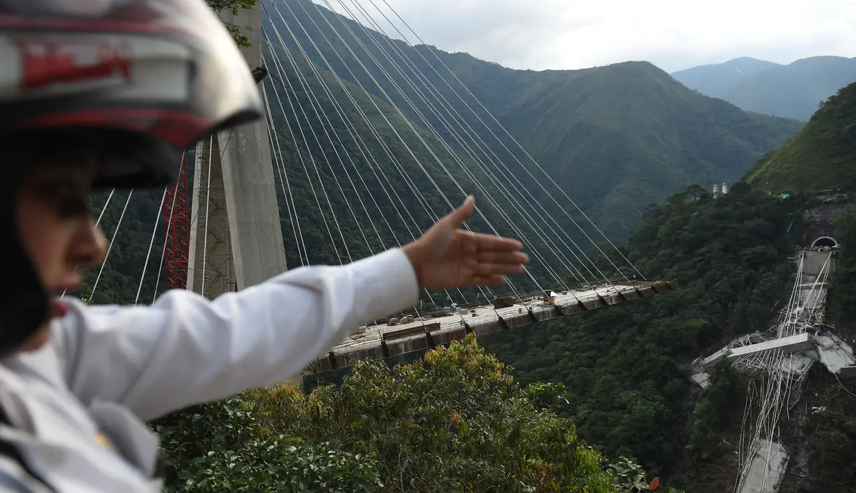 Seorang warga menunjukkan jembatan ambruk yang menghubungkan Bogota dengan Kota Villavicencio di kota Guayabetal, Senin (16/1).  Struktur jembatan tiba-tiba ambruk saat sekitar 35 atau 40 pekerja ada di lokasi tersebut. (Raul Arboleda/AFP)