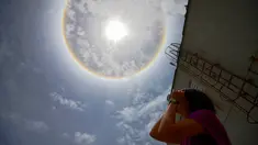 Seorang wanita mengamati fenomena Halo Matahari yang terjadi di atas langit kota Caracas, ibu kota Venezuela, 10 Mei 2016. Fenomena langka itu dinamakan Halo Matahari yang terbentuk akibat refleksi dari kristal es. (Juan BARRETO/AFP)