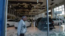 Warga berjalan melewati didinding sebuah dealer mobil yang pecah akibat serangan bom mobil di Diyarbakir, Turki bagian tenggara, Kamis (31/3). Empat personel kepolisian Turki tewas, sementara empat belas orang lainnya terluka. (Ilyas AKENGIN/AFP)