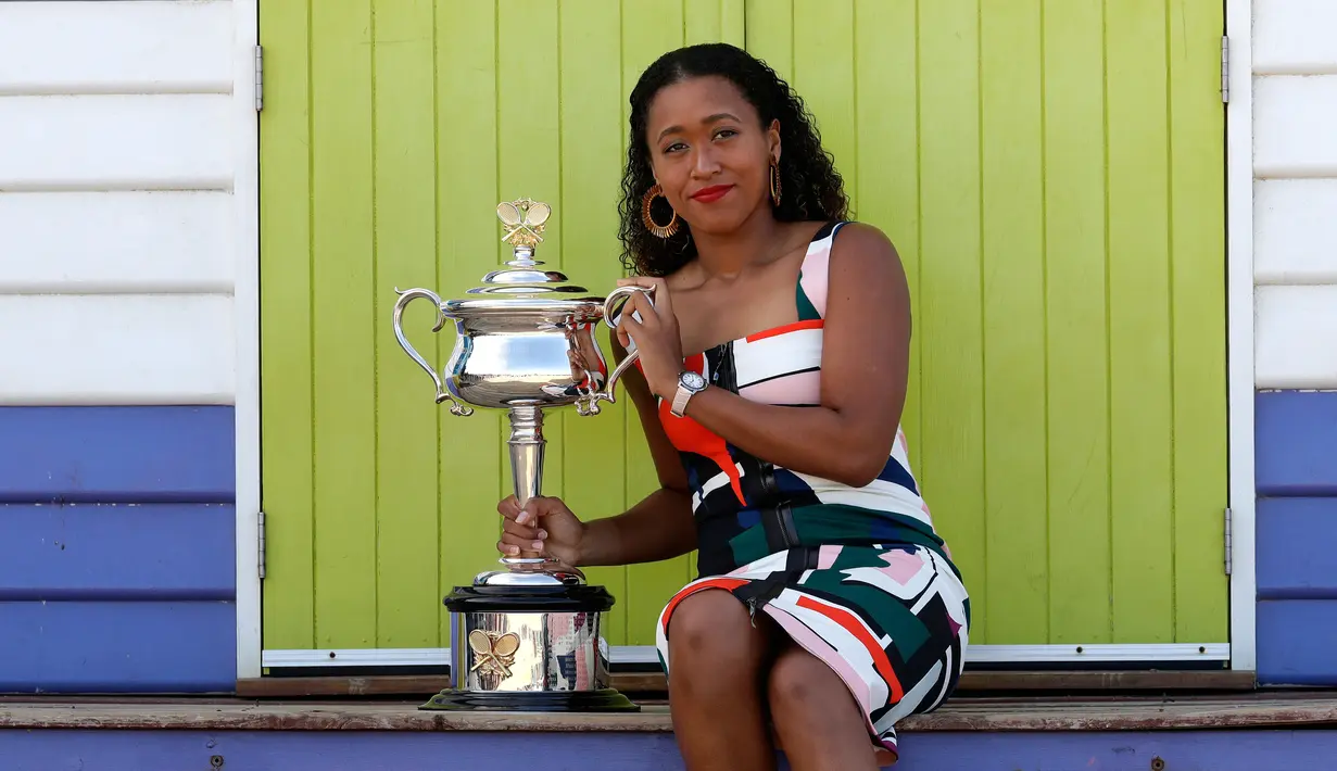 Petenis Jepang, Naomi Osaka menunjukkan trofi juara tunggal putri Australia Terbuka 2019 di Pantai Brighton Melbourne, Australia, Minggu (27/1). Osaka berhasil meraih kemenangan rubber set, 7-6, 5-7, dan 6-4 atas Petra Kvitova. (AP Photo/Kin Cheung)
