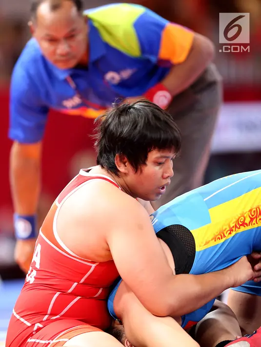 Pegulat putri Indonesia, Ridwan Ridha Wahyadaniyaty mengunci pegulat Kirgizstan Medet Kyzy Aiperi pada kelas putri 76 Kg di JCC Senayan, Selasa (21/8). Pada perdelapan final, Ridha kalah atas lawanya dengan skor 0-12. (Liputan6.com/Fery Pradolo)