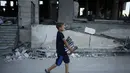 Seorang anak Palestina membawa salinan Alquran dari sebuah masjid yang rusak parah akibat serangan udara militer Israel, (9/8/2014). (REUTERS/Mohammed Salem)