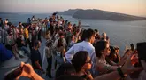 Wisatawan menunggu matahari terbenam di desa Oia di pulau Santorini, Yunani pada 20 Juli 2024. (Aris Oikonomou / AFP)