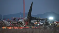 Petugas pemadam kebakaran dan penyelamat masih terus bekerja di dekat lokasi pesawat Jeju Air berjenis Boeing 737-800 yang jatuh dan terbakar di Bandara Internasional Muan, Provinsi Jeolla Selatan, sekitar 288 kilometer sebelah barat daya Seoul, Korea Selatan pada Minggu 29 Desember 2024. (JUNG YEON-JE/AFP)