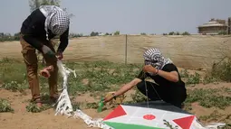 Warga Palestina mengikat bom molotov ke layang-layang di atas pagar perbatasan dengan Israel, di pinggiran timur Kota Gaza (20/4). Menerbangkan layang-layang dengan menggunakan bom molotov merupakan teknik baru warga Palestina. (AFP Photo/Mohammed Abed)