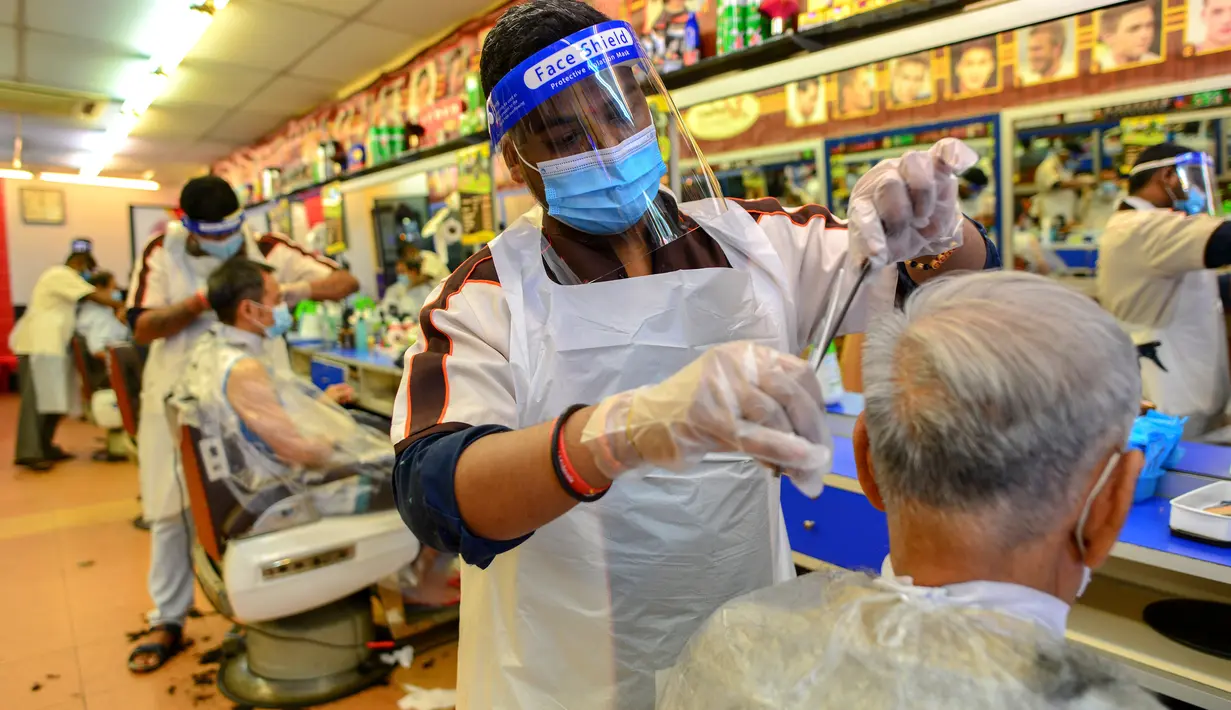 Para barber memangkas rambut pelanggan di sebuah tempat pangkas rambut di Kuala Lumpur, Juni 2020. Setelah hampir tiga bulan masa lockdown, pemerintah Malaysia melakukan pelonggaran sebagai upaya menghidupkan kembali perekonomian yang sempat terpukul akibat pandemi Covid-19. (Xinhua/Zhu Wei)