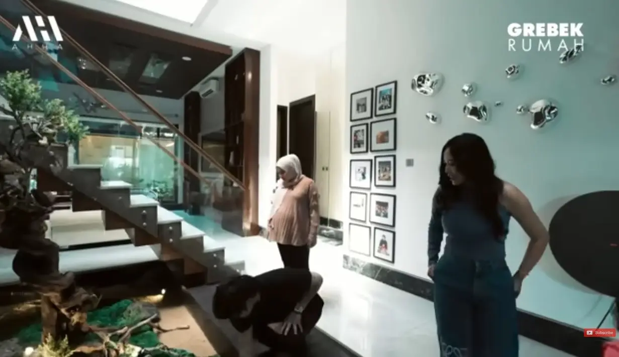 Rachel mengaku suka dengan unsur kayu. Bahkan, dalam ruangan tengah ini ada taman dan pohon besar di samping tangga. [Youtube/AH]