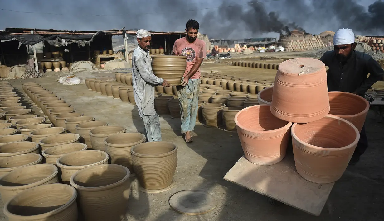 Pembuat tembikar menempatkan pot tanah liat untuk dikeringkan di sebuah bengkel di Karachi, Pakistan, Rabu (23/2/2022). (Rizwan TABASSUM/AFP)