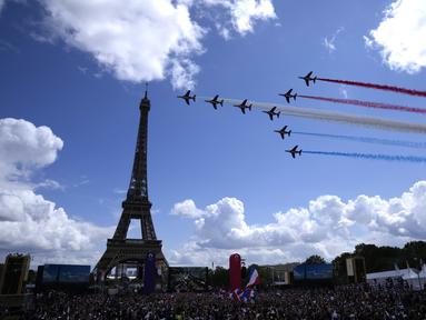 Jet dari angkatan udara Prancis Patrouille de France terbang di atas Menara Eiffel dan melewati zona penggemar Olimpiade di Paris, Minggu (8/8/2021). Perayaan diadakan di Paris Minggu sebagai bagian dari upacara serah terima Tokyo 2020 ke Paris 2024. (AP Photo/Francois Mori)