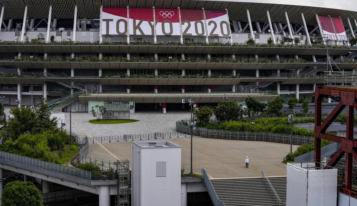 Seorang pekerja berjalan melalui pintu depan Stadion Nasional, satu bulan sebelum pembukaan Olimpiade Tokyo, di Tokyo, Rabu (23/6/2021). Olimpiade Tokyo dimulai pada 23 Juli dan penyelenggara mengizinkan penonton lokal menghadiri venue pertandingan dengan kapasitas 50 persen (AP Photo/Kiichiro Sato)