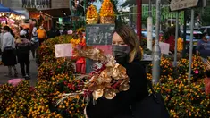 Seorang wanita membeli bunga untuk merayakan Tahun Baru Imlek di Hong Kong, Rabu (19/1/2022). Tahun Baru Imlek China jatuh pada 1 Februari 2022. (AP Photo/Kin Cheung)