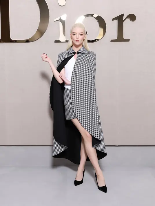 Anya-Taylor Joy tampil estetik dengan atasan putih berlapis cape kotak-kotak yang serasi dengan rok [Dior]