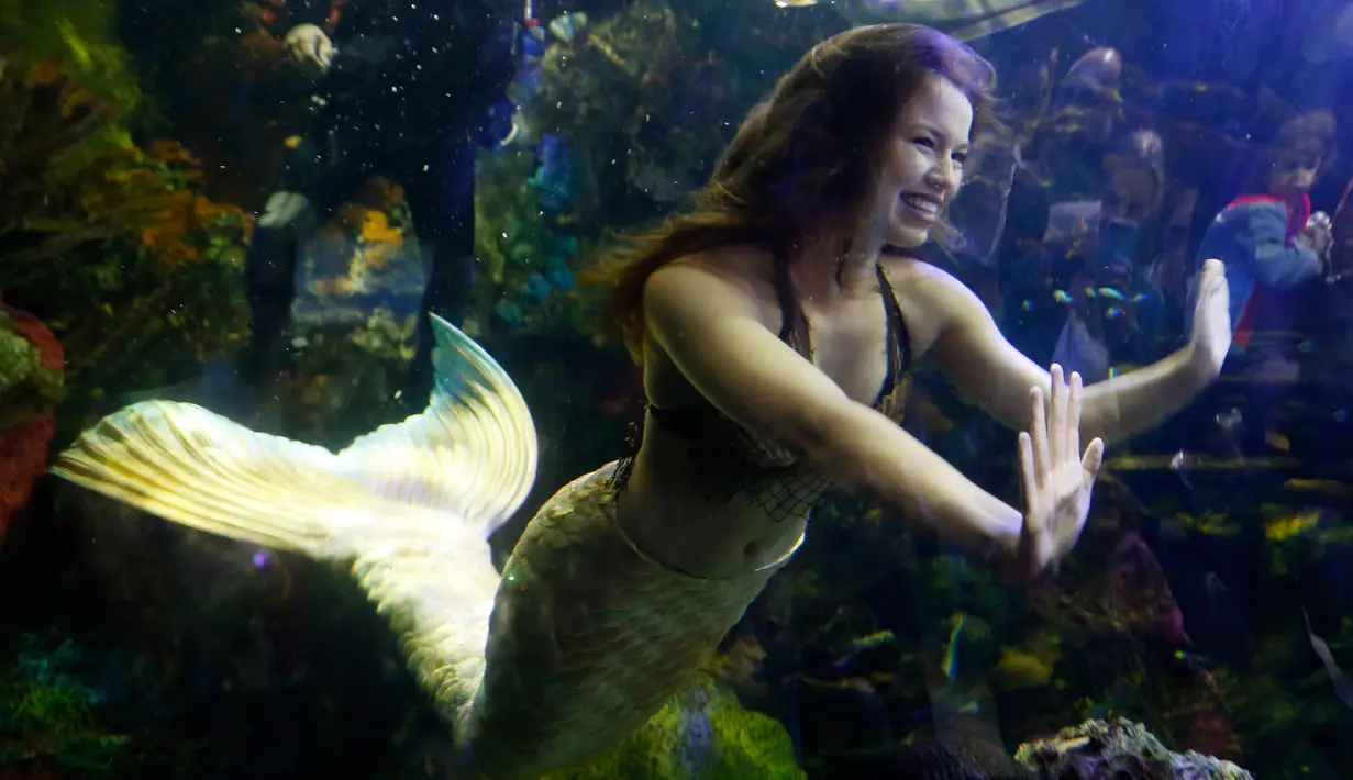 Putri duyung Hales Parcels berinteraksi dengan anak-anak yang menonton penampilannya di Virginia Aquarium di Virginia Beach (3/4). Hales Parcels tampil berenang menggunakan pakaian ala putri duyung. (AP Photo/Steve Helber)