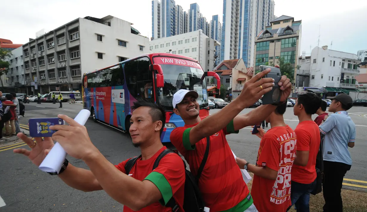 Ratusan suporter mendatangi Stadion Jalan Besar, Singapura untuk menyaksikan laga timnas Indonesia U-23 melawan Kamboja, Sabtu (6/6/2015). Beberapa suporter ber-selfie berlatar bus pemain timnas Indonesia U-23. (Liputan6.com/Helmi Fithriansyah)