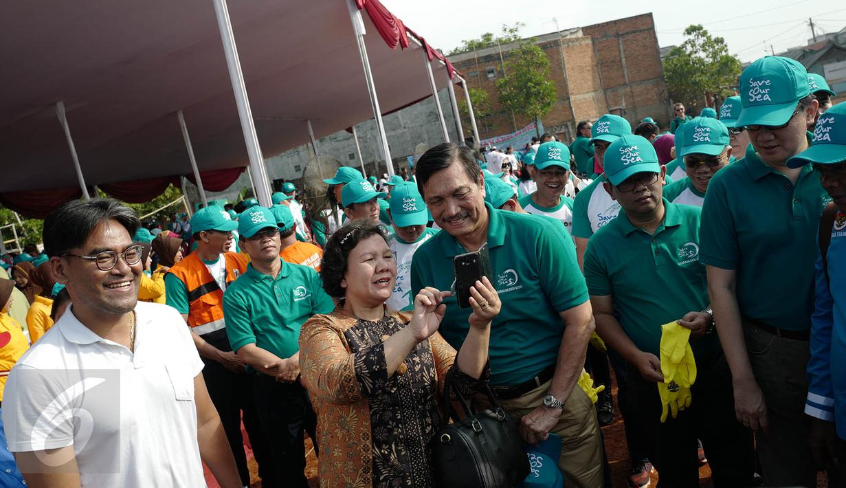 Menteri Koordinator Bidang Kemaritiman Luhut Binsar Panjaitan berfoto bersama seorang warga saat menggelar gerakan aksi bersih di kawasan pesisir Cilincing, Jakarta Utara, Sabtu (6/4). (Liputan6.com/Immanuel Antonius)