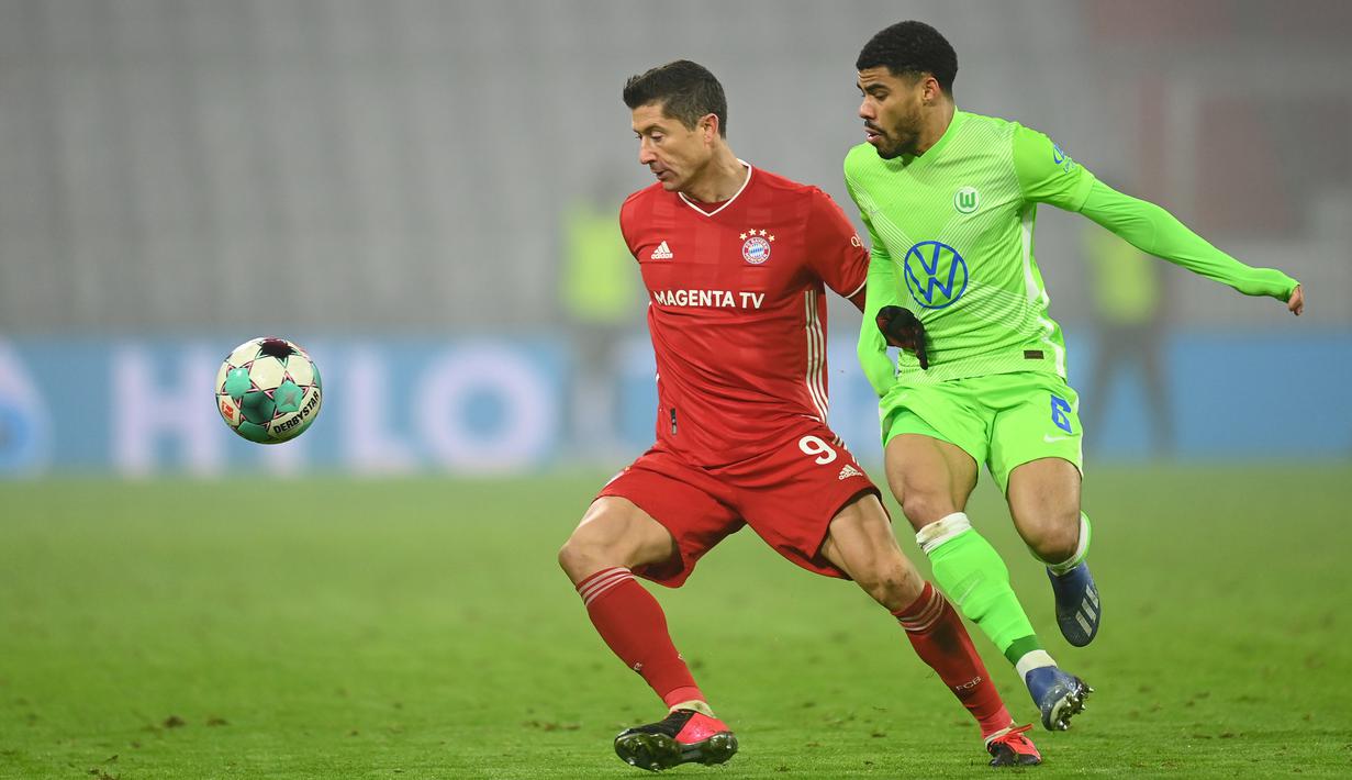 Penyerang Bayern Munchen, Robert Lewandowski, berebut bola dengan bek Wolfsburg, Paulo Otavio, pada laga lanjutan Liga Jerman di Allianz Arena, Kamis (17/12/2020) dini hari WIB. Bayern Munchen menang 2-1 atas Wolfsburg. (AFP/Christof Stache/pool)