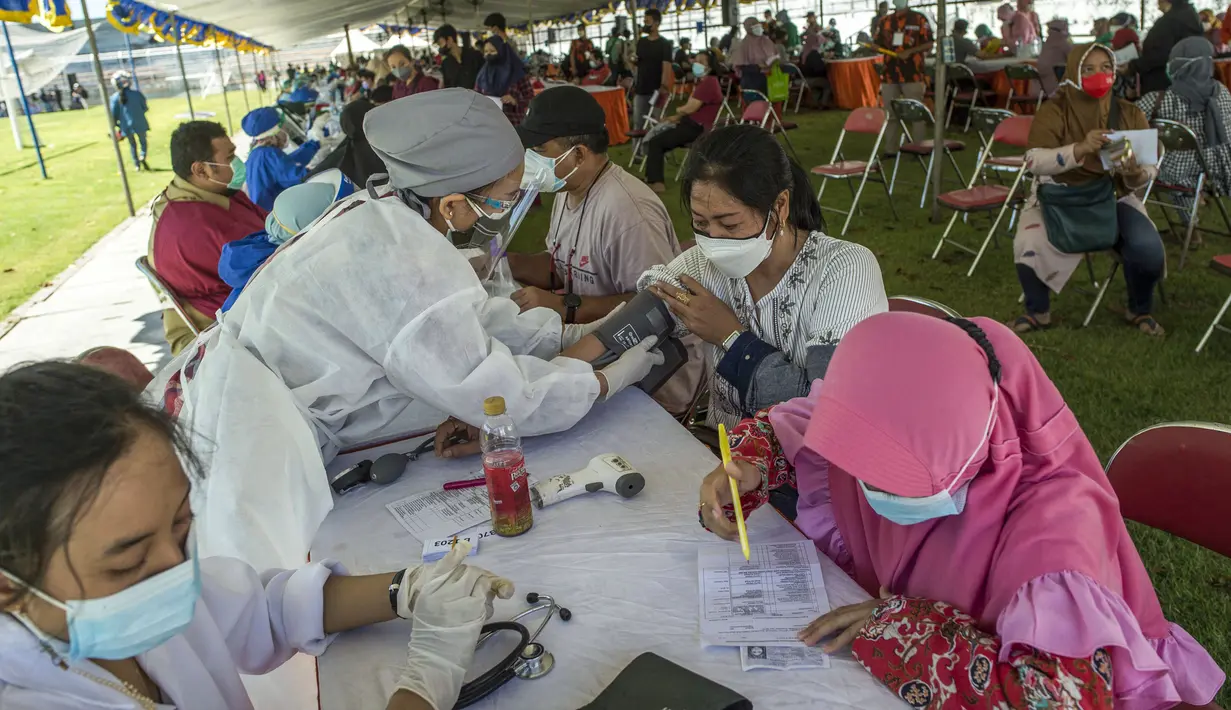 Dokter memeriksa kondisi warga di klinik vaksinasi massal darurat di lapangan sepak bola di Surabaya, Jawa Timur, Selasa (6/7/2021). Indonesia tengah memerangi gelombang infeksi baru yang belum pernah terjadi sebelumnya. (JUNI KRISWANTO/AFP)