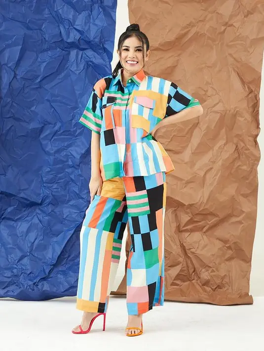 Tampil fashionable, Nindy Ayunda mengenakan set kemeja dan celana panjang berwarna biru yang memiliki tabrak garis. Outfit ini makin playful dengan heels beda yang dikenakannya (instagram/nindyayunda)