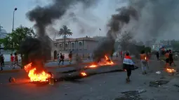 Demonstran antipemerintah melakukan pembakaran saat protes di dekat Alun-Alun Tahrir, Baghdad, Irak, Senin (27/7/2020). Perdana Menteri Irak mengatakan telah memerintahkan penyelidikan atas pembunuhan dua demonstran antipemerintah. (AP Photo/Hadi Mizban)
