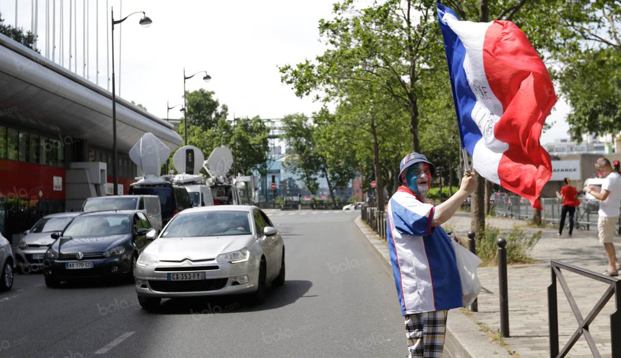 Seorang fans bernama Patrick, mengibarkan bendera Prancis saat menunggu keberangkatan tim ayam jantan dari hotel. (Bola.com/Vitalis Yogi Trisna)