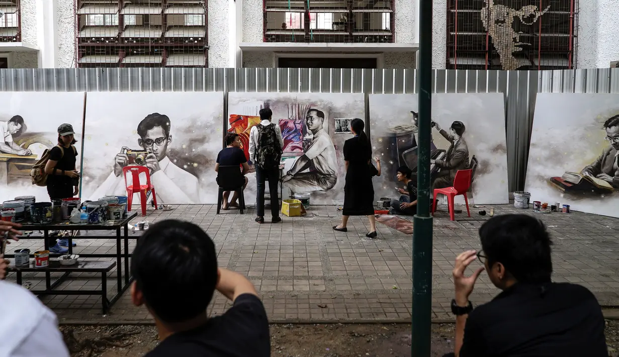 Para mahasiswa seni dari Universitas Silpakorn menyelesaikan lukisan gambar mendiang raja Bhumibol Adulyadej, disaksikan beberapa pengunjung di Bangkok, Senin (17/10). (Reuters/Athit Perawongmetha)