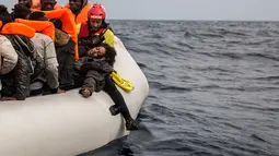 Seorang wanita saat diselamatkan petugas dari LSM Spanyol Proactiva Open Arms, setelah meninggalkan Libya yang mencoba mencapai tanah Eropa di atas sebuah kapal karet yang penuh sesak, 60 mil sebelah utara Al-Khums, Libya (18/2). (AP Photo/Olmo Calvo)