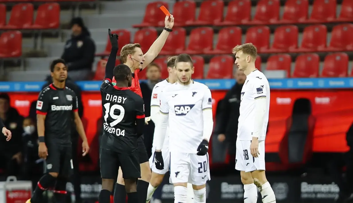 Pemain Hoffenheim Stefan Posch mendapat kartu merah dari wasit Martin Petersen saat melawan Bayer Leverkusen pada pertandingan Bundesliga di Leverkusen, Jerman, 13 Desember 2020. Bayer Leverkusen menggeser Bayern Munchen dari puncak klesemen usai mengalahkan Hoffenheim. (THILO SCHMUELGEN/POOL/AFP)