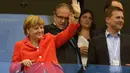 Dari atas tribun kehormatan, Kanselir Jerman, Angela Merkel menyapa tim Der Panzer yang berlaga melawan Portugal di penyisihan Piala Dunia Grup G di Fonte Nova Arena, Brasil, (16/6/2014). (AFP PHOTO/Fabrice Coffrini)